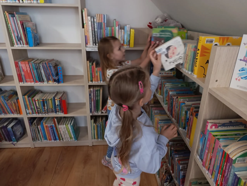 Przedszkolaki oglądają książki na regale