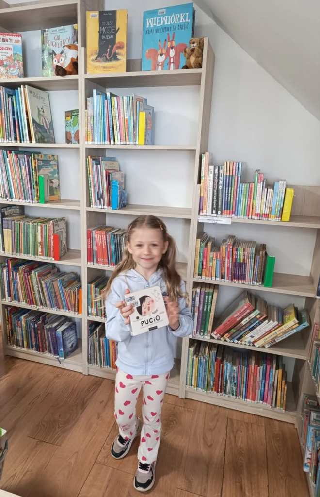 Mała czytelniczka wśród bibliotecznych półek