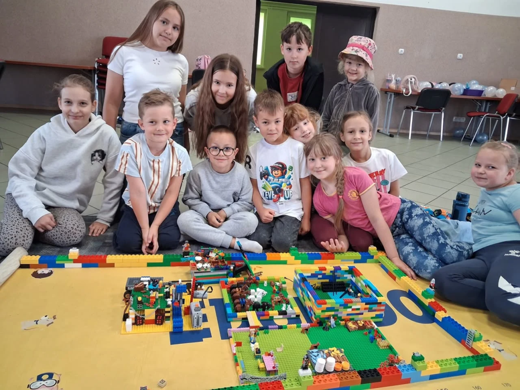 Grupa dzieci z opiekunką podczas warsztatów LEGO
